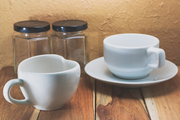 Two coffee cup and Empty jar on a wooden. Process color with vin