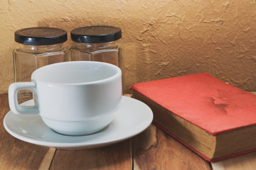 White coffee cup, Empty jar and a book on a wooden. Process colo