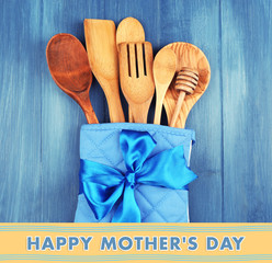 Different kitchen utensils in potholder on wooden background, Mother's Day greeting card