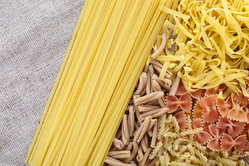 Different types of pasta on sackcloth background