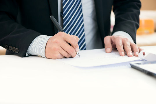 Image of businessman's hands laying on table with pen