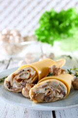 Pancakes with cream and mushrooms on wooden table, closeup