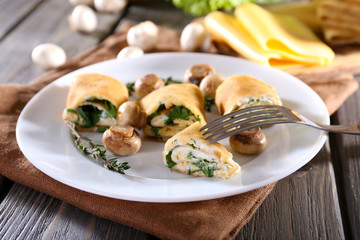 Pancakes with creamy mushrooms in plate on wooden table, closeup