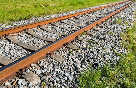 Rusty orange colored railroad rails diagonally in the image