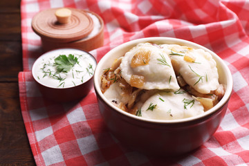 Tasty dumplings with fried onion in brown bowl,