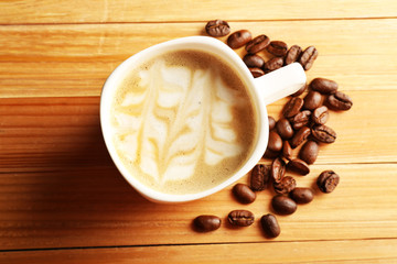 Cup of coffee latte art with grains on wooden table, top view