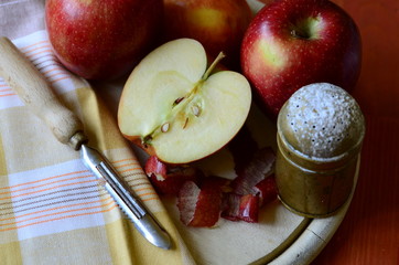 Sugar shaker, apples and peel knife on wooden chopping board