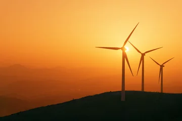 Foto auf Acrylglas Mühlen Windkraftanlagen Silhouette auf dem Berg bei Sonnenuntergang