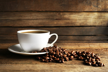 Cup of coffee with grains on wooden background