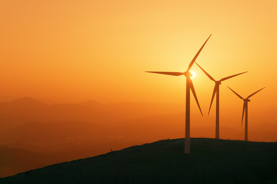 Wind Turbines Silhouette On Mountain At Sunset