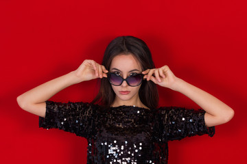 Beautiful brunette girl in a black dress and sunglasses.