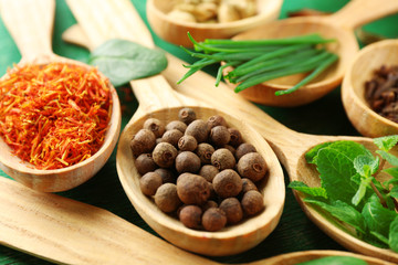 Wooden spoons with fresh herbs and spices on wooden background