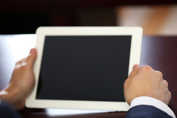 Businessman working with tablet at wooden table, closeup