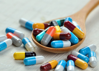 pills in the spoon on white wooden background
