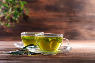 Cups of green tea on table on wooden background