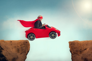 senior superheld rijdt een auto uit een ravijn