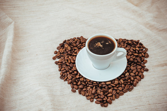 Cup of Coffee and roasted beans in heart shape isolated on white