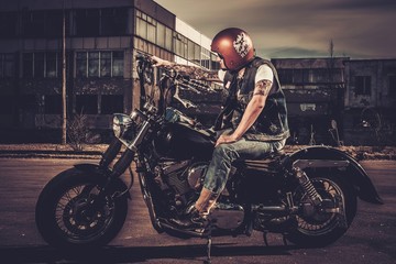 Biker and his bobber style motorcycle on a city streets - obrazy, fototapety, plakaty