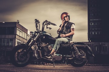 Fototapeta premium Biker and his bobber style motorcycle on a city streets