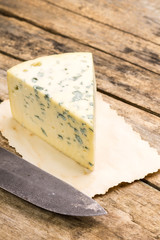 Blue cheese with old rural knife on wooden table.