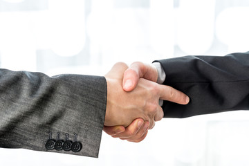 Two businessmen shaking hands over a blurred abstract background