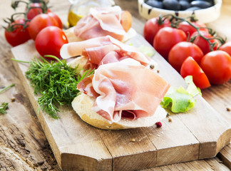 Prosciutto Ham Appetizer with Spices on a Wooden Cutting Board