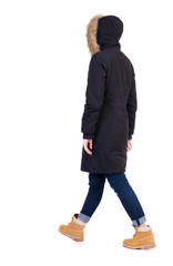 Naklejka premium Back view of going woman in parka.