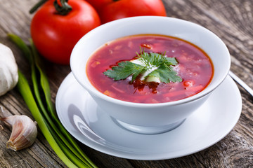Borsch with bread on a wooden background.