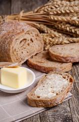 Tasty bread with wheat on wooden background.