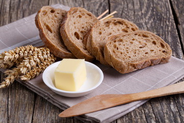 Tasty bread with wheat on wooden background.