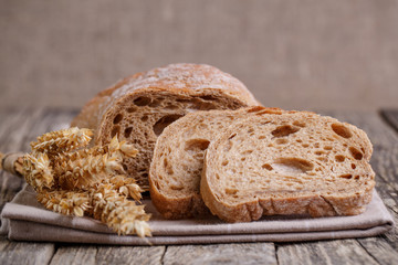 Tasty bread with wheat on wooden background.