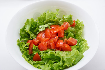Healthy green salad, tomatoes in white bowl.