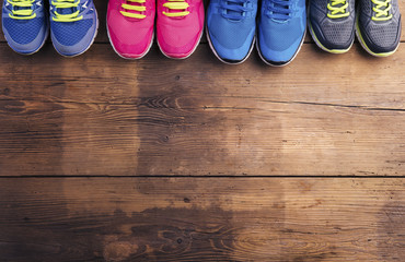Various running shoes laid on a wooden floor background