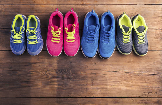 Various running shoes laid on a wooden floor background