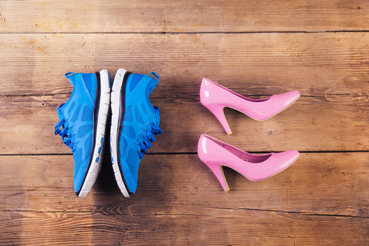 Running shoes and pink court shoes on a wooden background