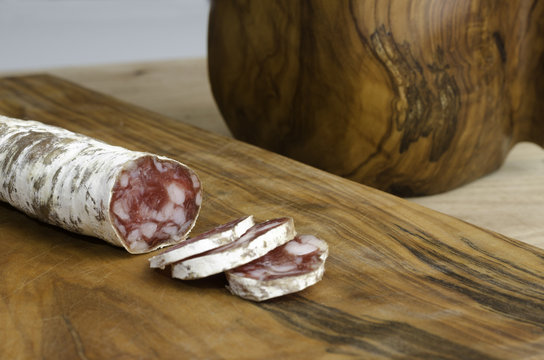 SSpanish fuet salami over rustic wooden cutting board.