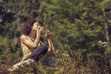 Fototapeta premium Peaceful woman gently touching and smelling wild mountain plants