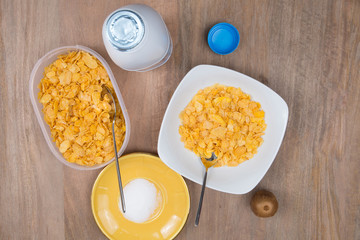 Cornflakes with milk, eggs,  on a wooden brown background