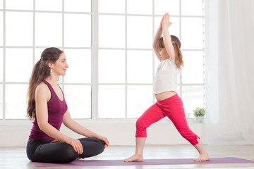 Fototapeta na wymiar Young mother and daughter doing yoga exercise
