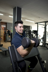 Fototapeta na wymiar Young man training biceps at gym center