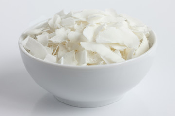 Coconut flakes in white ceramic bowl. In perspective.