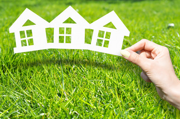 Home insurance concept with hand on green grass