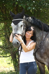 Naklejka premium Portrait of beautiful woman and gray horse in garden