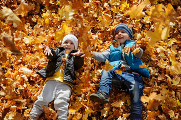 Happy children in autumn park lying on leaves