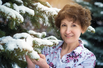 Portrait of a beautiful woman near the fir in the snow. Closeup