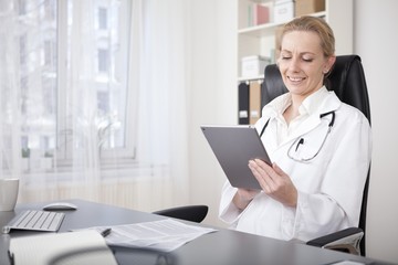 Obraz na płótnie Canvas Happy Woman Physician Using her Tablet Device