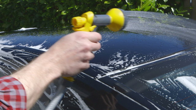 Car Care - Man using a garden spray gun