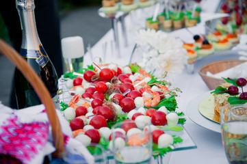 Table with fruits on stand and tableware on stand-up party