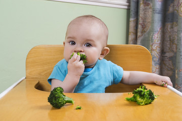 Cute baby eating broccoli