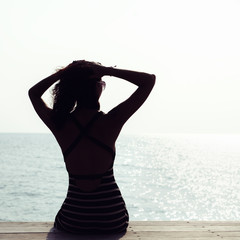 Young pretty woman sitting alone on the pier